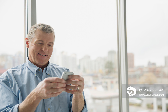 Casual businessman texting on smartphone in office