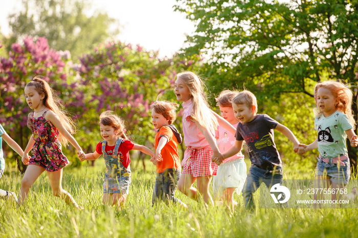 在一个阳光明媚的夏日，一群快乐的男孩和女孩在公园的草地上奔跑。