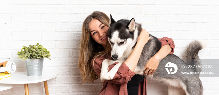 Young pretty woman with her husky dog sitting in the floor at indoors