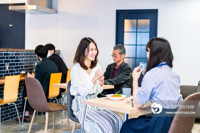 明るい雰囲気の社員食堂でランチを取るオフィスワーカー