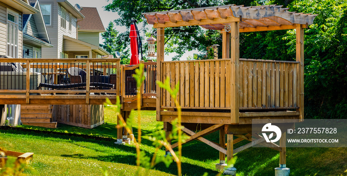 Raised backyard wooden deck and gazebo behind a row of houses