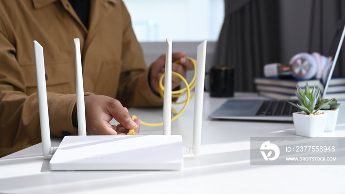 Close up view of man plugs internet cable into the router. Wireless internet concept.