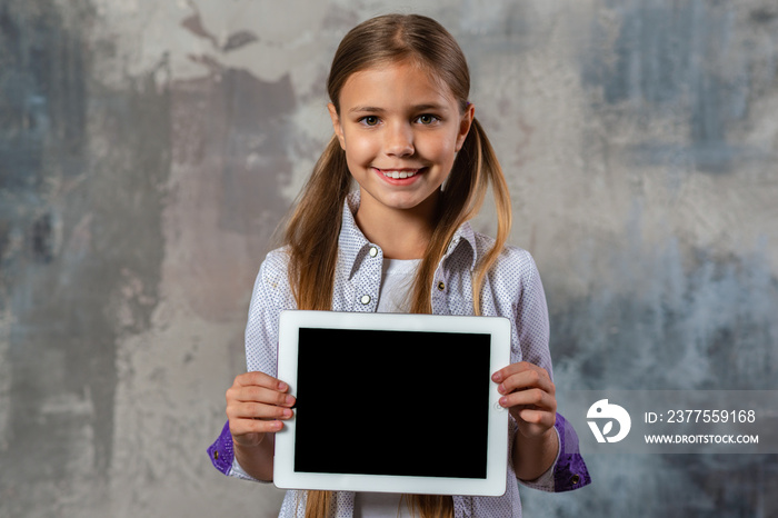 Smiling blonde girl holding ipad in her hands and looking at the camera. - Horizontal image mockup