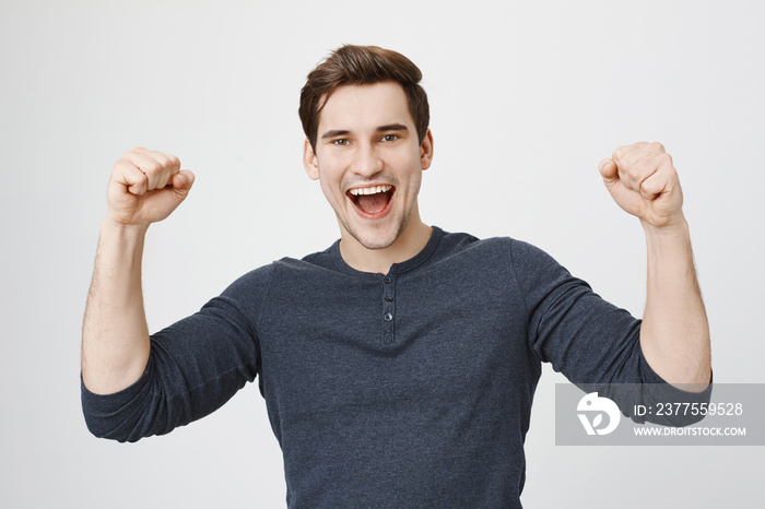 Portrait of cheerful dark-haired attractive European unshaven male being excited and glad to achieve