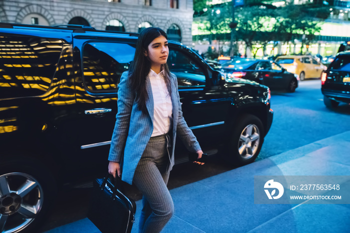 Businesswoman walking near black SUV at night