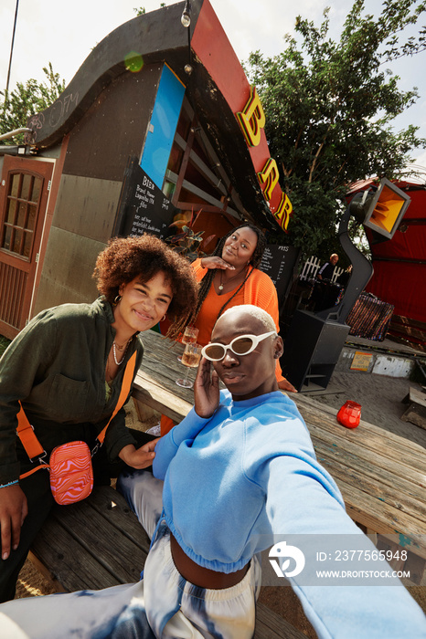 Portrait of female friends posing for selfie outside bar