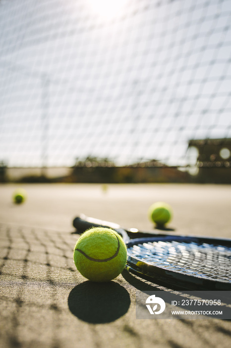 Close up of a tennis racket and balls lying on a court