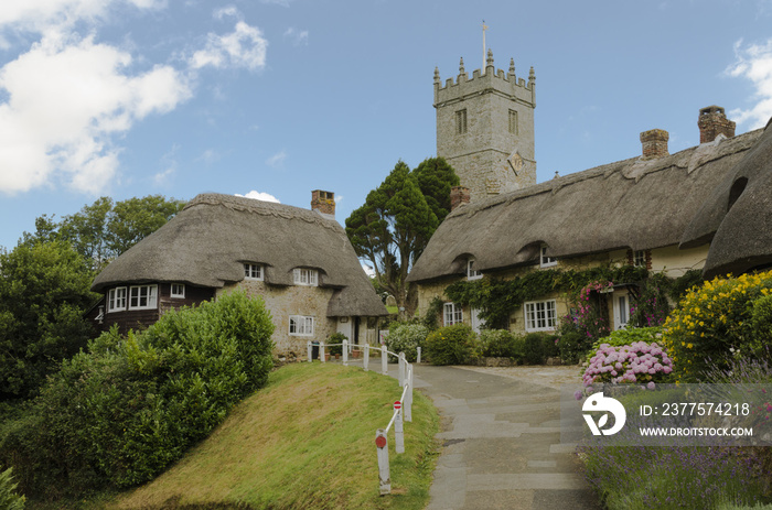 The pretty thatched cottages of Church Hill, with All Saints church in the background.l