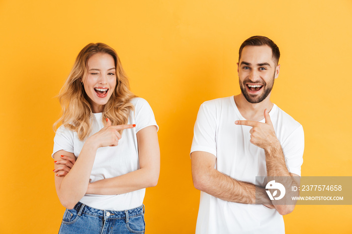 Excited cheerful young couple standing isolated