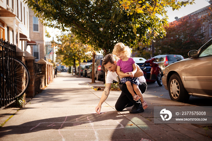 Father with his daughter drawing on pavement