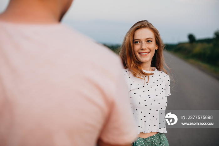 Portrait of a freckled woman smiling and looking into the eyes of her boyfriend holding her hand and