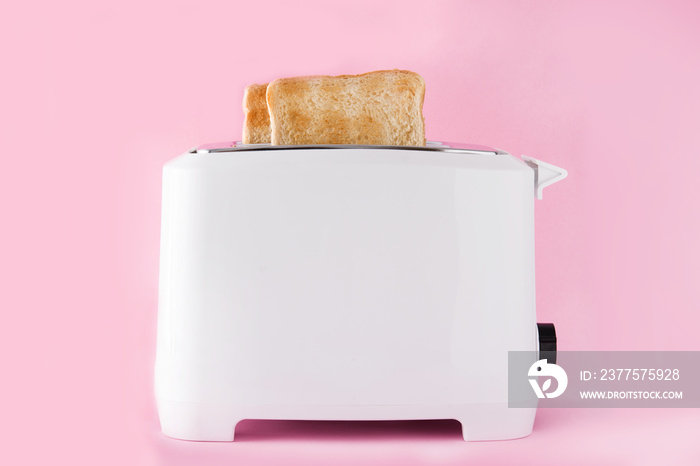 Toasted toast bread in white toaster on pink background