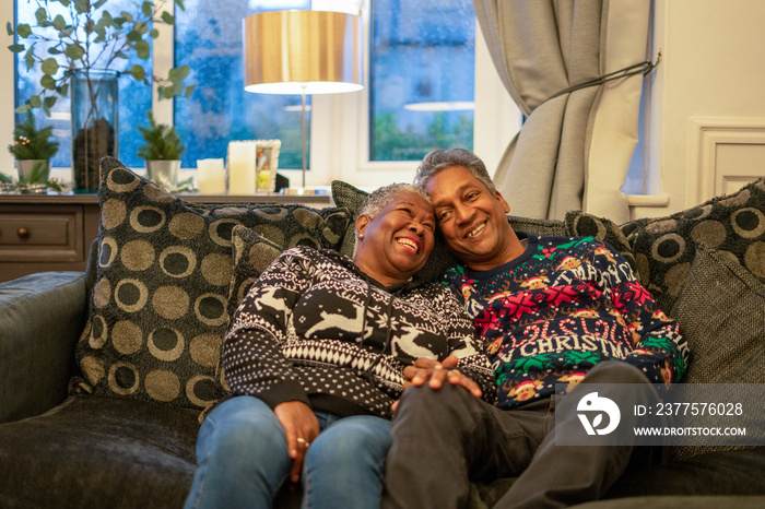 Senior couple sitting on sofa and being affectionate