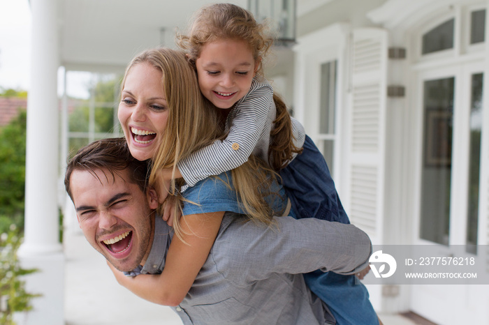 Portrait happy family piggybacking on patio