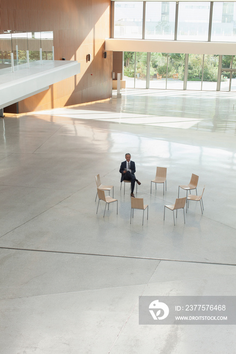 Businessman waiting in circle of chairs in modern lobby