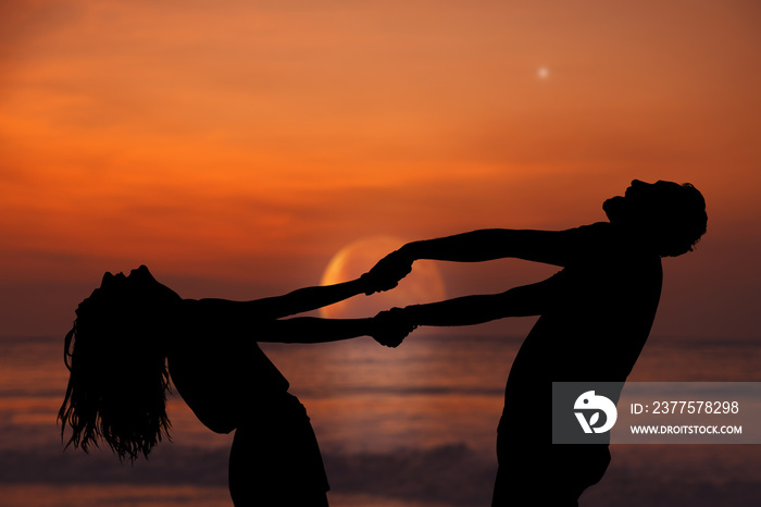 Silhouettes of a couple dancing under the rising Moon and stars over the ocean / sea horizon. My ast