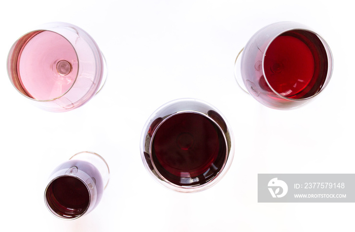 Four glasses of wine: red and pink on white background with sparkling shadows. Top view. Free copy s