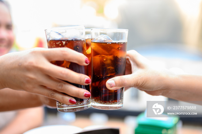 女人的手拿着一杯黑色软饮料要喝。