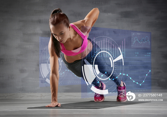 Sporty young woman making exercise on gray background