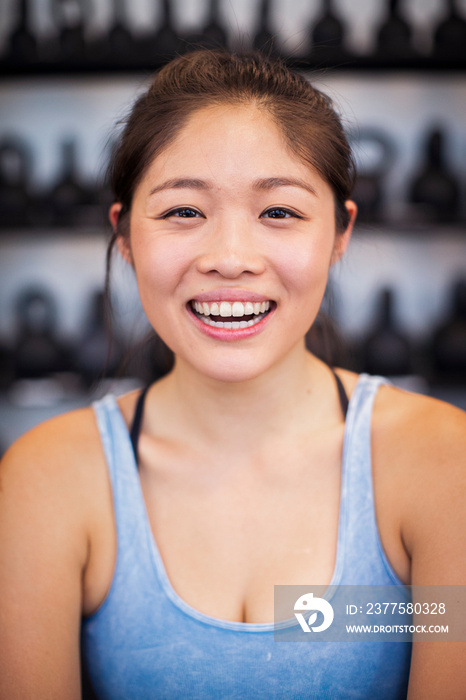 Close-up portrait of happy female athlete sitting in gym