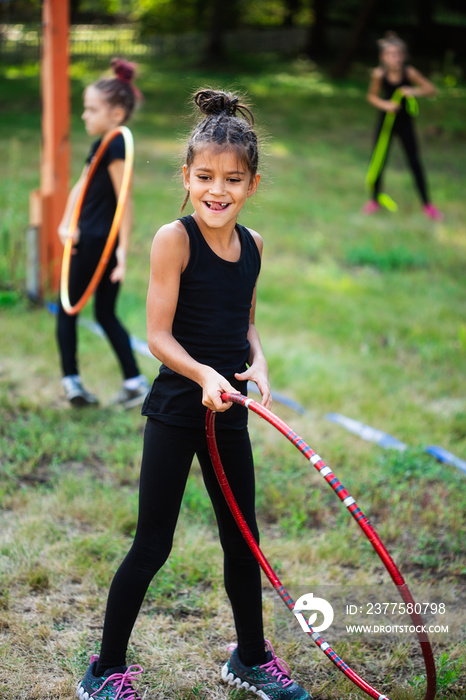 Girl gymnast training with hoop and smiling on sports playground