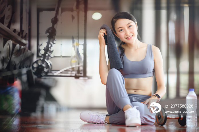 Woman exercise workout in gym fitness breaking relax holding towel, smiling and looking at camera