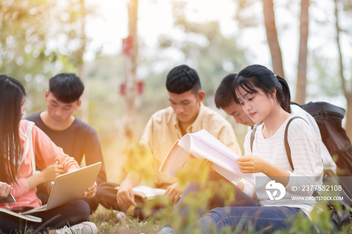 教育学习学习户外概念：自信的亚洲学生群体坐着看书，使用标签