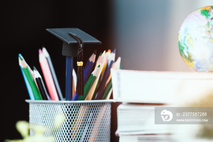 Education Graduate study concept: Black Graduation hat on pencils, blur of europe earth world globe 