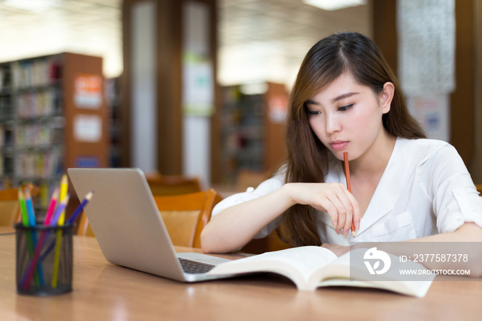 亚洲美女女学生在图书馆用笔记本电脑学习