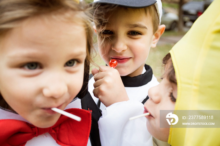 Close up of children in costumes eating lollipops