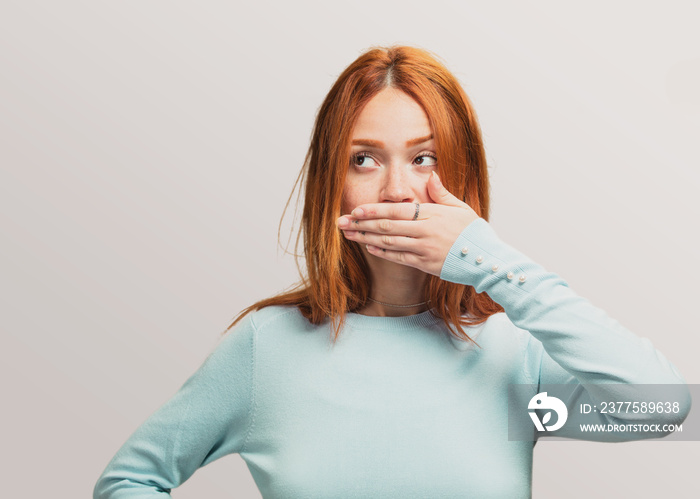 portrait of a pretty redhead girl covering her mouth