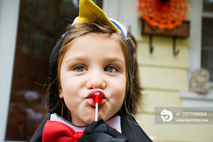 Close up of girl in costume eating lollipop