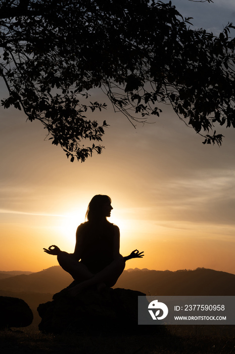 Silhouette of a  young woman practicing yoga alone on the mountains with a beautiful sunset