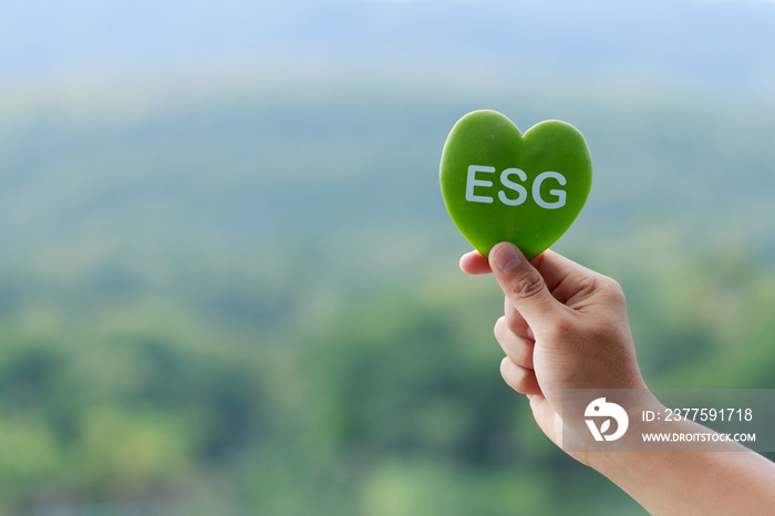 环保背景上带有ESG文本符号的手持绿叶，