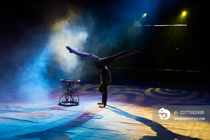 Acrobat performs a difficult trick in the circus.