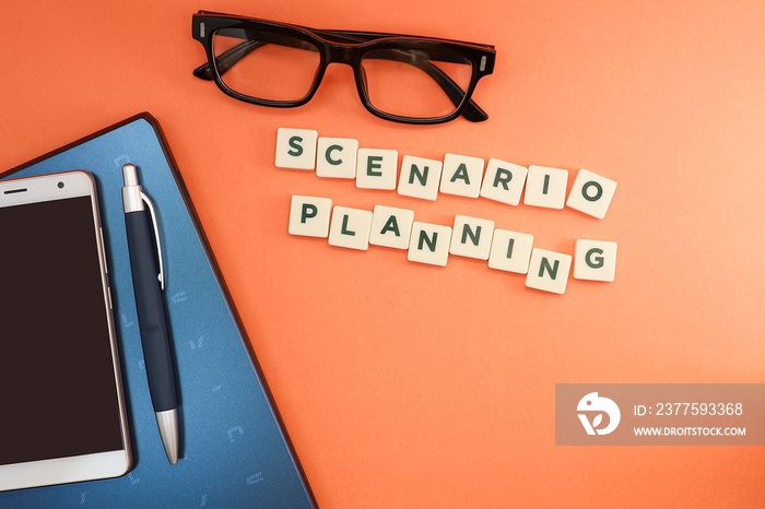 Text on scenario planning on the orange background with eyeglasses, laptop, and a pen