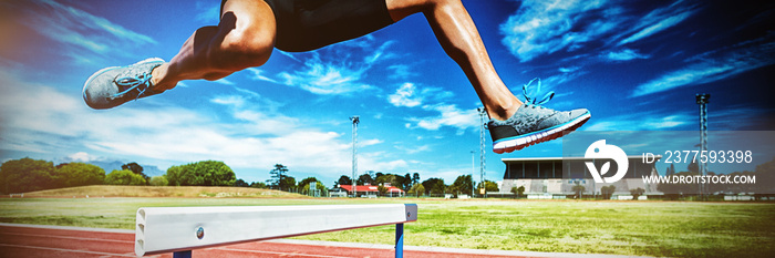 Female athlete jumping above the hurdle