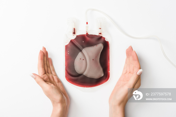 Cropped view of woman holding drip with blood on white background, blood donation concept