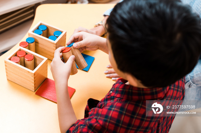 蒙台梭利学校的孩子和老师在桌子上玩木制游戏的选择性焦点，俯视图