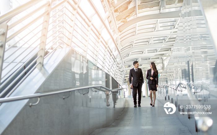 Two business man and woman talking and walking outside