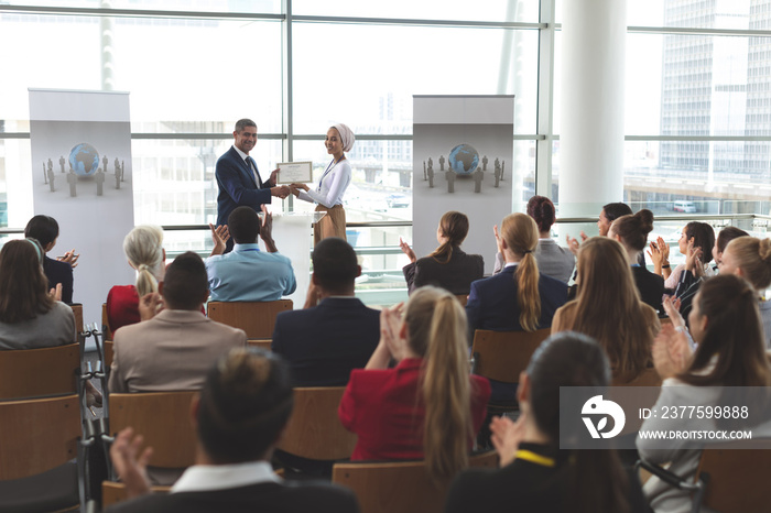 Businesswoman receiving award from businessman in a business seminar