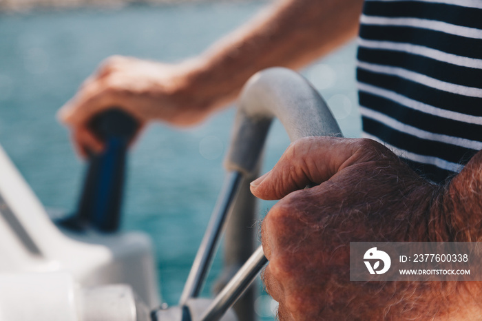 Close-up view of a Senior Man hands driving a little boat - Captain