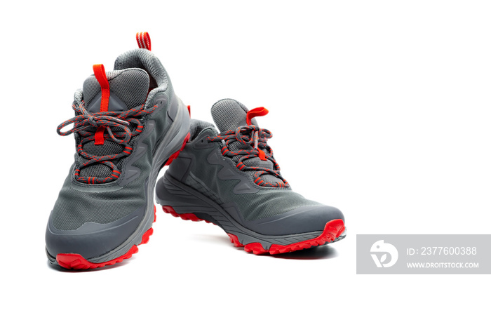 Men trekking shoes isolated on white background. Gray-red hiking shoes. Safety footwear for climbing. Adventure gear. Lightweight rubber trekking shoes with safety sole. Modern and breathable design.