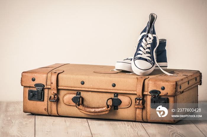 Sneakers on top of an old brown suitcase with a retro effect