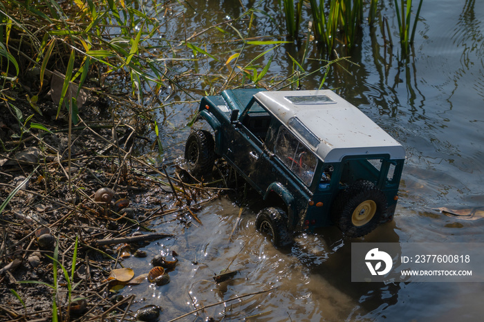 RC Radio controlled truck moves over an obstacle driving along on the rock with coast and river