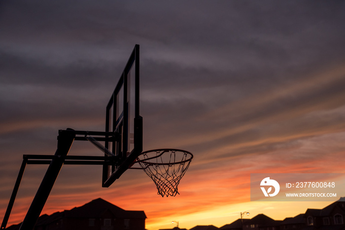 Basketball backboard and  hoop rim silhouette with sunset in the background