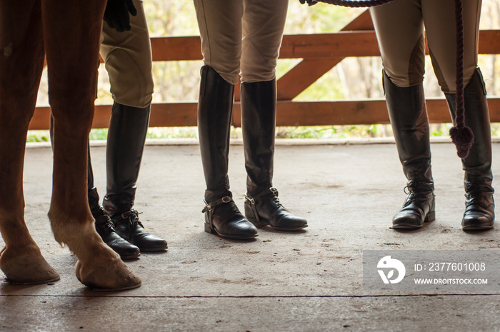 Boots and horse hooves on barn floor