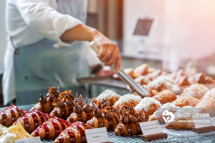 Delicious croissants on the store showcase of the bakery shop with blur seller background in the shop, Small business at home, Work from home. Selective focus.