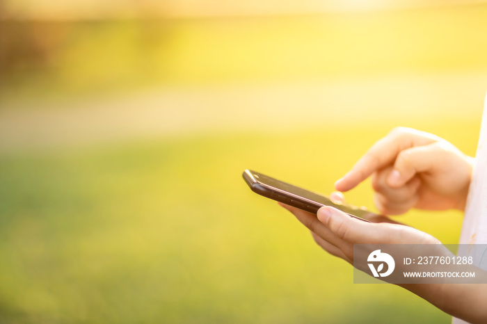 Close-up of female working using smartphone blurred images in Abstract inside green bokeh background at the park, Summer abstract theme