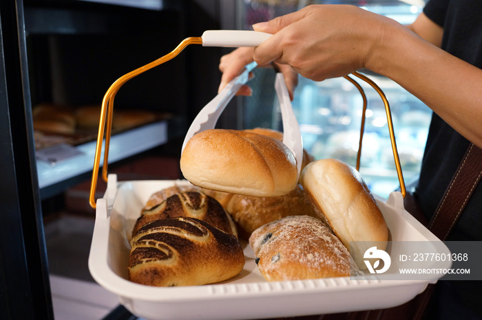 Close up of hands of female taking a tray of bread and pastry from the counter in a bakery store.